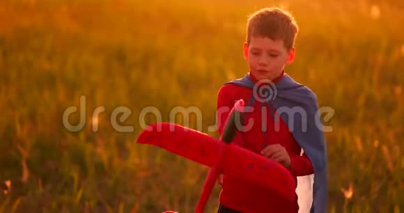 日落时分男孩手里拿着一架飞机在田里玩耍视频的预览图