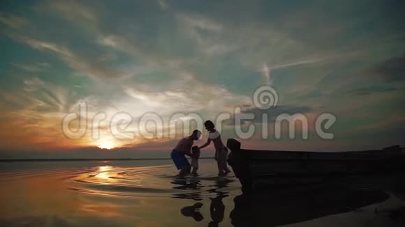 日落时分家人在湖边玩耍小朋友和家长的剪影们下一在一起跑步和玩耍慢慢视频的预览图