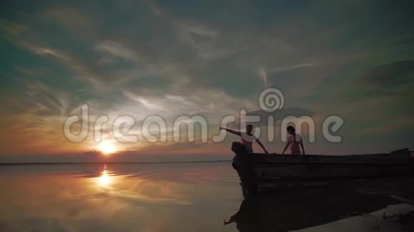 日落时分在湖边散步小朋友和家长的剪影下一次在一起跑步和玩耍视频的预览图