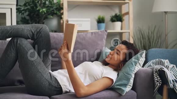 聪明的非裔美国女孩专注于读书小说躺在沙发上享受休闲活动和娱乐视频的预览图