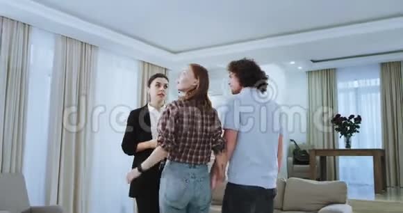 女屋代理向一对魅力十足的夫妇展示新的现代公寓她用平板电脑代表房子视频的预览图