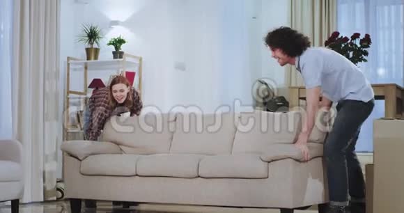 年轻漂亮的一对夫妇在新房子里享受时光他们兴奋地把沙发搬到客厅中间视频的预览图