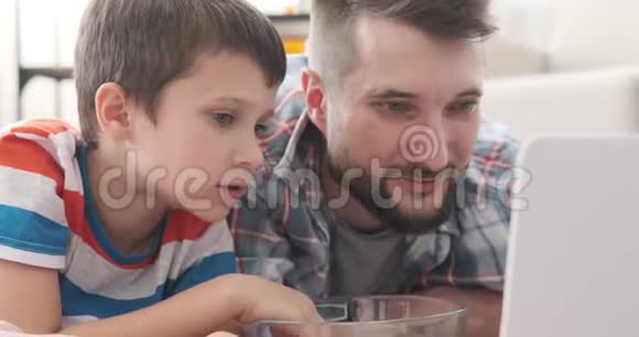 父亲和儿子一起欣赏笔记本电脑的电影视频的预览图