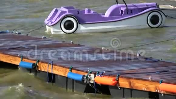 紫罗兰色塑料船形状为汽车在海上和木墩在波浪上视频的预览图