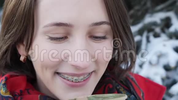 这段视频讲述的是一个女孩在冬天在街上喝热茶或咖啡时的特写镜头她穿着针织手套视频的预览图