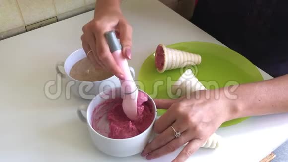 一个女人在喇叭里加了草莓冰淇淋用冰淇淋勺放在盘子上桌子上有集装箱和视频的预览图