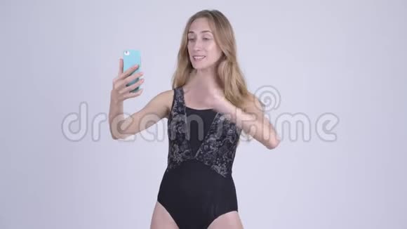 穿着泳装的年轻金发美女带着电话视频的预览图