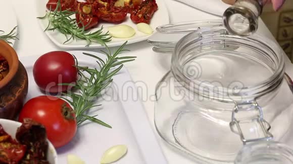 用香料和大蒜晒干的西红柿为了保存它们一个女人把橄榄油倒在罐子里加入盐和香料在附近视频的预览图