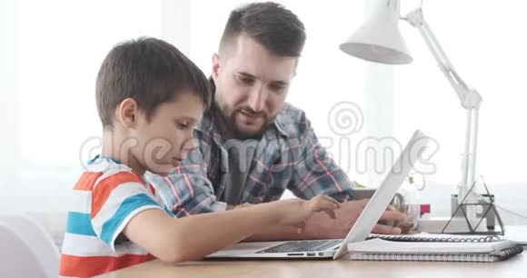 父亲和儿子学习使用笔记本电脑视频的预览图