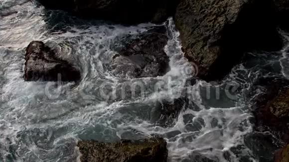 海浪冲击海岸上的石头溅起的水花和泡沫向上跳跃形成了美丽的海洋色彩和图案视频的预览图