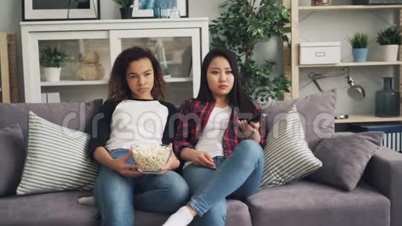 无聊的年轻女人在家里一起看电视在客厅里坐在沙发上吃爆米花亚洲女孩视频的预览图