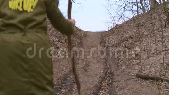 从森林到小山跑出去一个穿夹克的少年站了起来手里拿着一根棍子就像一个徒步旅行者视频的预览图