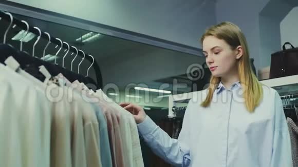 年轻漂亮的女孩在精品店挑选衣服买视频的预览图
