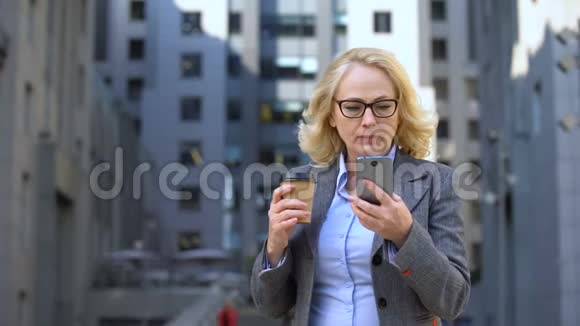 担心的女经理看智能手机新闻喝杯咖啡科技视频的预览图