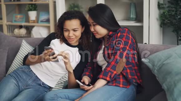无忧无虑的年轻女性正在玩着智能手机看着屏幕谈笑风生地享受着网络和视频的预览图