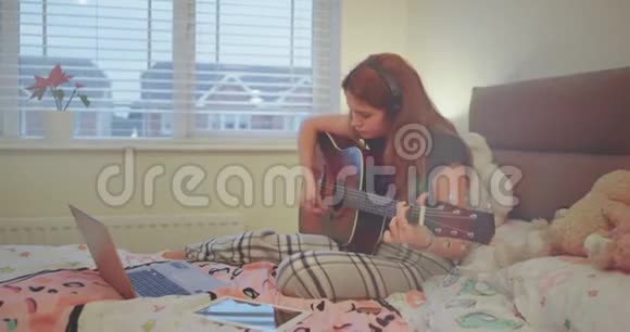 可爱的年轻女士在卧室里弹吉他穿着睡衣和自己相处得很愉快视频的预览图