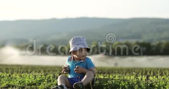 可爱的宝宝在农田灌溉设备的背景下玩耍视频的预览图