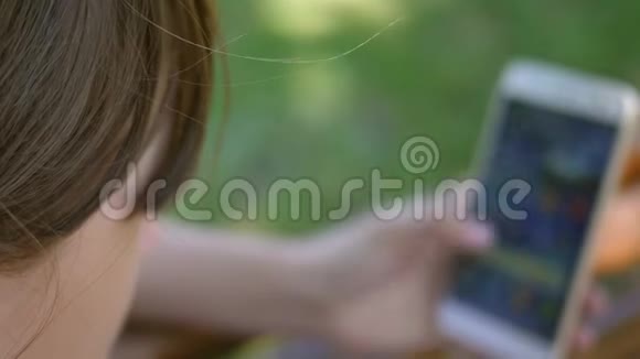 女孩在Instagram上落叶美丽的女孩用智能手机在一个美丽的绿色公园的长凳上写一封信视频的预览图