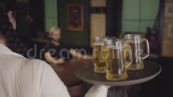一个漂亮的甜胖女孩在一家啤酒餐厅的托盘上放着三杯啤酒女服务员给两个人带了啤酒视频的预览图