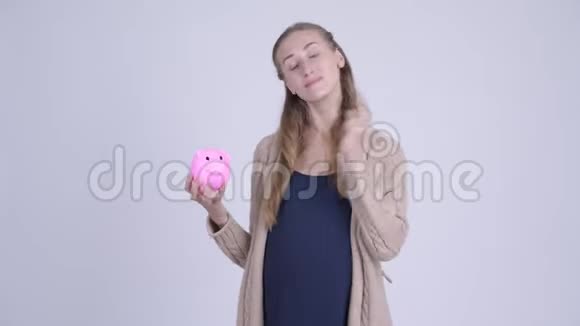 幸福的年轻孕妇手里拿着储蓄罐竖起大拇指视频的预览图