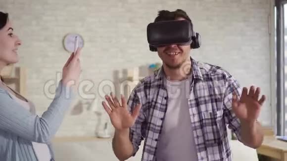 年轻女子在手机上用虚拟现实眼镜拍摄男人的反应视频的预览图
