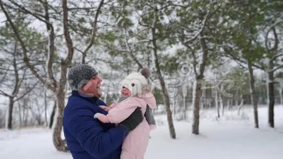 父亲在下雪的冬天把他可爱的女儿抛在空中父母把他的孩子扔上去然后抓住视频的预览图