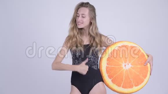 穿着泳衣竖起大拇指用橙色枕头做健康的概念视频的预览图