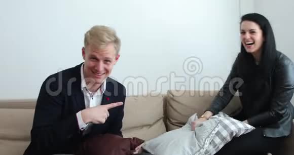 英俊的金发男人和漂亮的女人在沙发上打枕头战妻子赢了视频的预览图