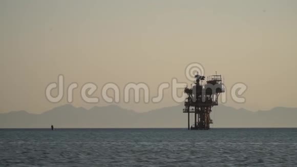 巨大的石油钻井平台在海上雾山的背景傍晚视频的预览图