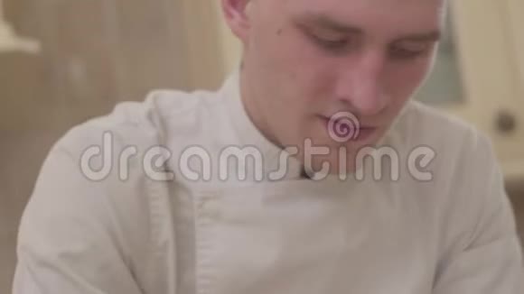 年轻的比萨饼师穿着厨师制服在厨房里捏着比萨饼皮准备食物慢动作视频的预览图