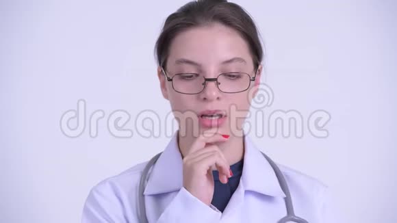 一张严肃的年轻女医生的脸思考着低头看着视频的预览图