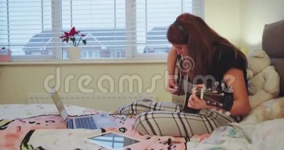 在一个漂亮的房间里一个十几岁的女孩开始弹吉他躺在床上非常集中地度过了一段美好的时光视频的预览图