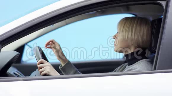 金发女人穿着休闲装驾驶着绿色屏幕背景的汽车4她正坐在车上喝着酒视频的预览图