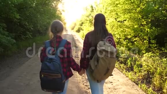 徒步旅行者女孩女孩带着背包在乡间公路上旅行女游客去看日落假期快乐的家庭视频的预览图