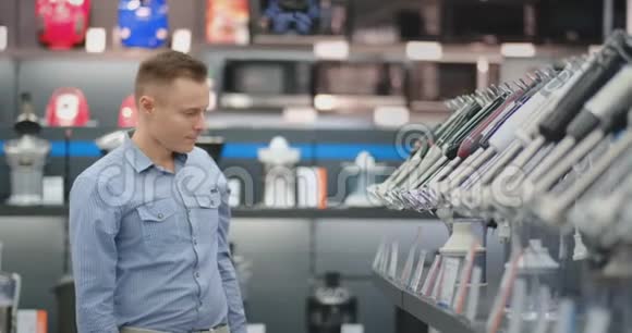一个穿着衬衫的年轻人在一家消费电子商店里为他的厨房搅拌机视频的预览图