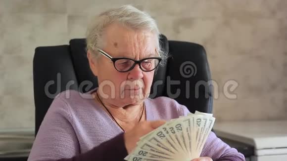 幸福的老人手里拿着钱一位老妇人手中的美元视频的预览图