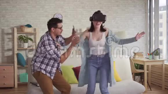 年轻人在手机上用虚拟现实眼镜拍摄女人的反应视频的预览图
