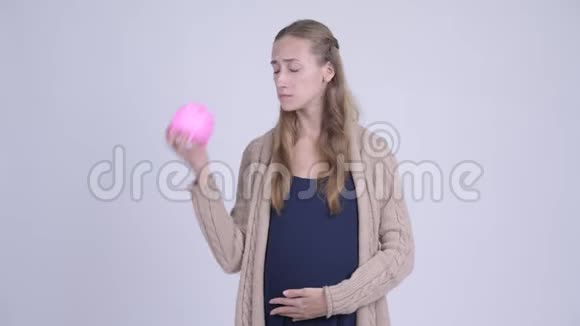 穿着衣服的年轻孕妇拿着储蓄罐竖起大拇指视频的预览图