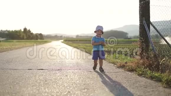 夏天漂亮的孩子在田野附近玩耍一个小男孩沿着马路跑视频的预览图