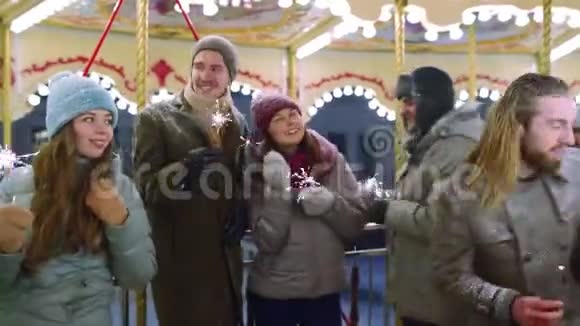 微笑的朋友在圣诞节市场上玩旋转木马的火花新年快乐的男人和女人视频的预览图