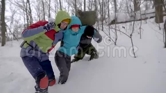 徒步旅行者帮助受伤的朋友在雪中行走视频的预览图