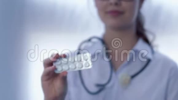 未聚焦的白色背景下女性医生手中的药丸视频的预览图