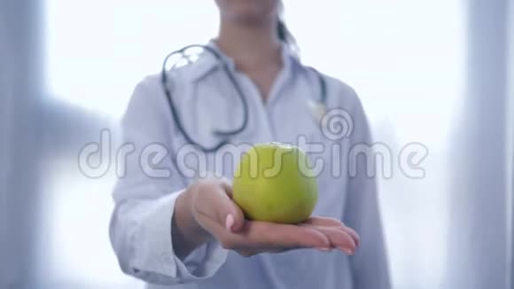 专业的食物专家手中拿着绿苹果给相机建议健康饮食没有重点视频的预览图