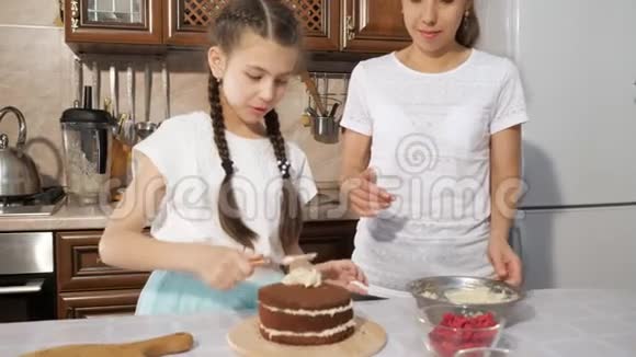 母亲和女儿用刀子在巧克力海绵蛋糕上抹上白色奶油视频的预览图