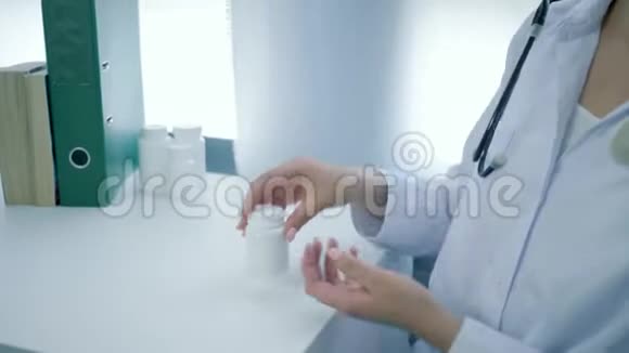 营养师的双手打开一瓶维生素将黄色的圆形药丸倒入白色桌子上的手掌中视频的预览图