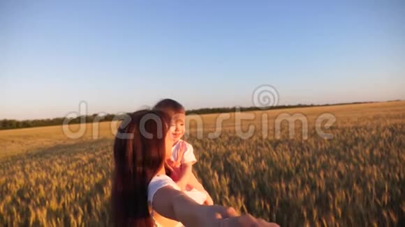 幸福的家庭牵着手在麦田里奔跑慢动作母女俩笑着旅行牵手视频的预览图