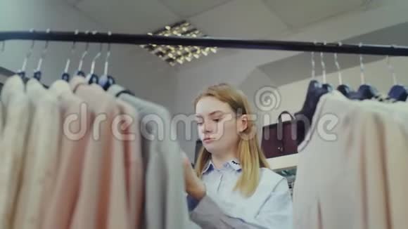 年轻女子看着衣服挂在衣架上视频的预览图