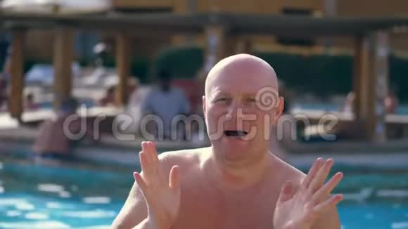 肖像滑稽的秃顶中年男子赤裸的躯干有趣的唱歌跳舞在游泳池度假在视频的预览图