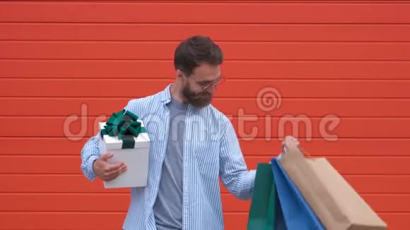 有胡子和胡子的人拿着购物袋红色背景在销售季节买东西的人打折男子视频的预览图