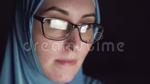 穆斯林妇女戴着头巾戴着眼镜晚上在黑暗中集中露面的肖像在互联网上搜索视频的预览图
